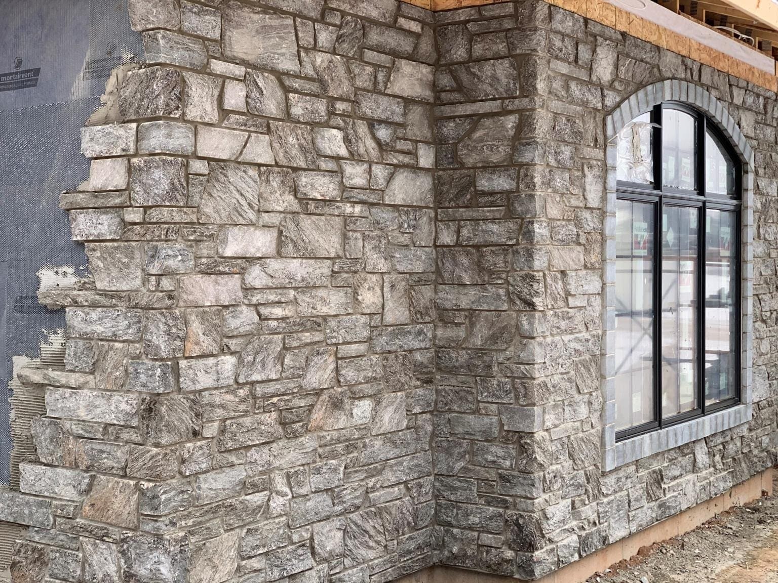 Dimensional natural stone veneer being installed on a residential exterior