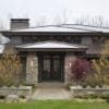 Curb View of Residential Home with Smokey Gold Pillars, Wainscoting, and Landscape Wall